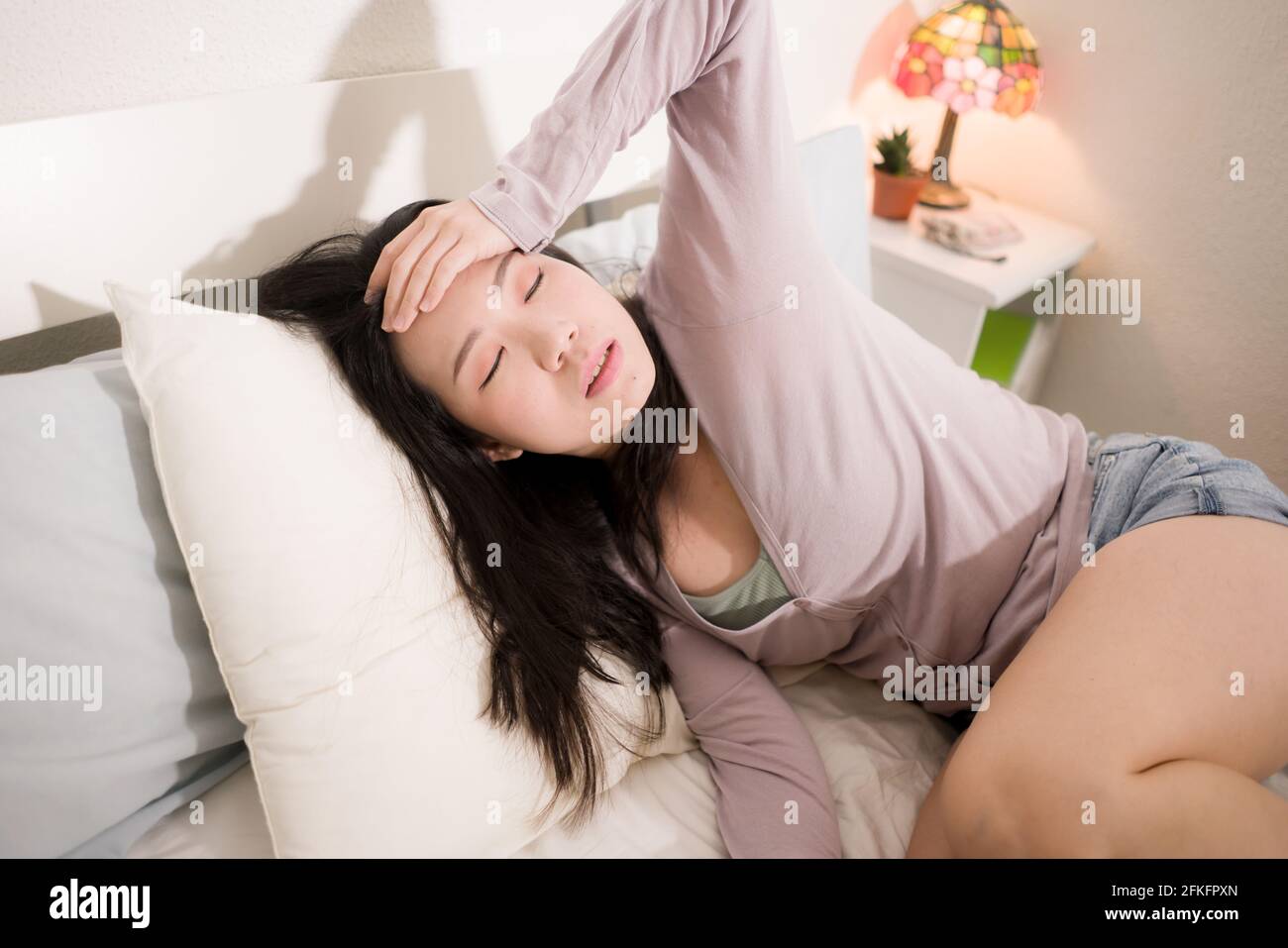 young Asian woman depressed - young beautiful and sad  Japanese girl on bed with pillow feeling unhappy and broken heart suffering depression problem Stock Photo