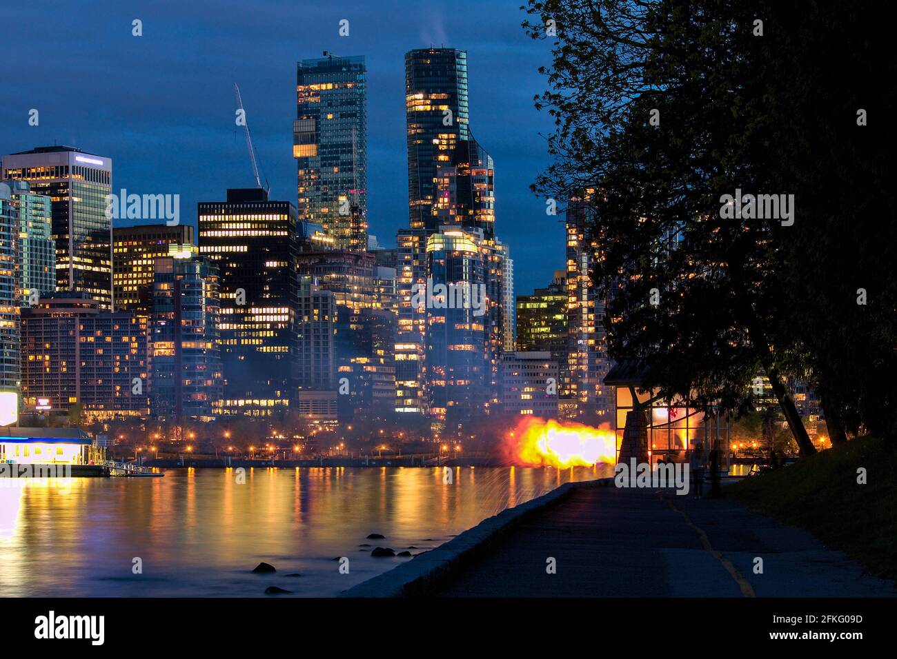 Vancouver Nine O'Clock Gun firing in dark during blue hour with cityscape in the background, Stanley Park, Vancouver, BC, Canada. Stock Photo
