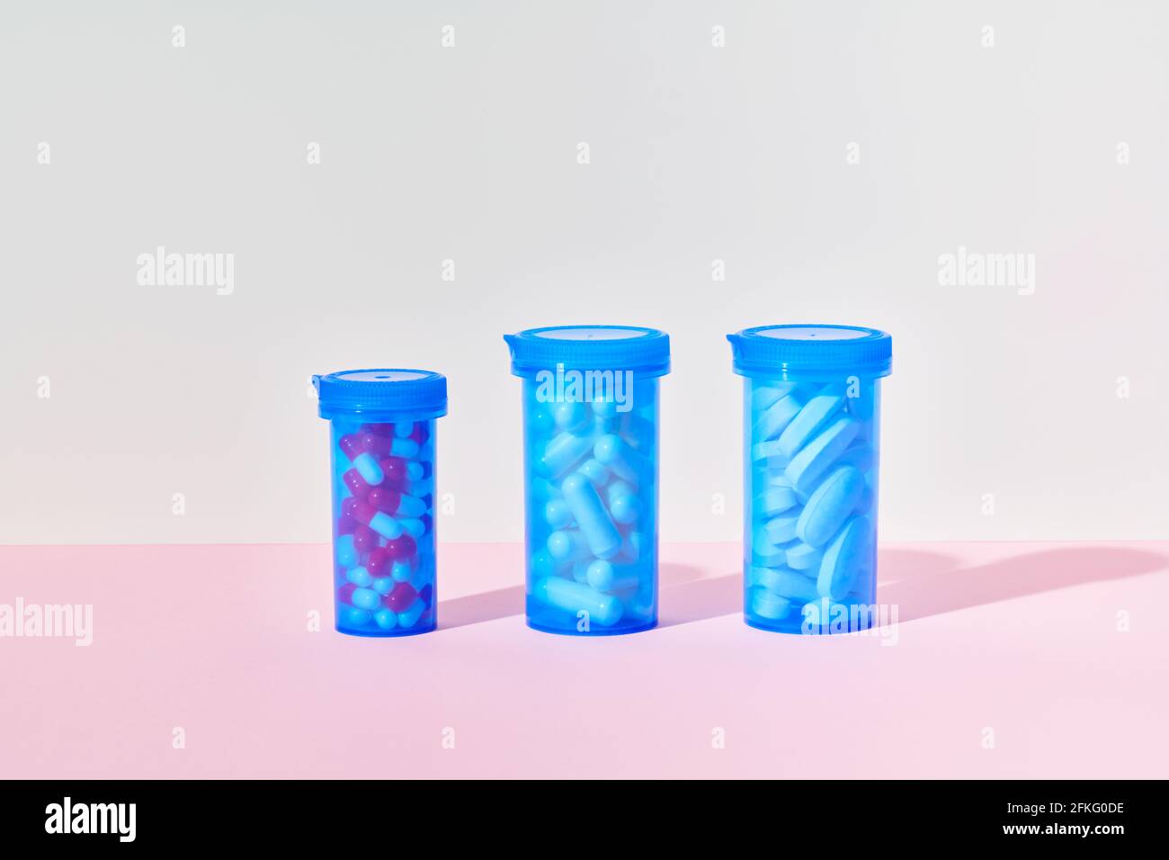 Bottles of medicine pills and capsules on pink background Stock Photo