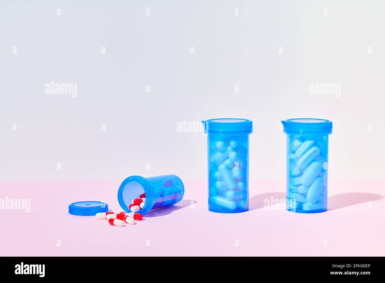 Bottles of medicine pills and capsules on pink background Stock Photo