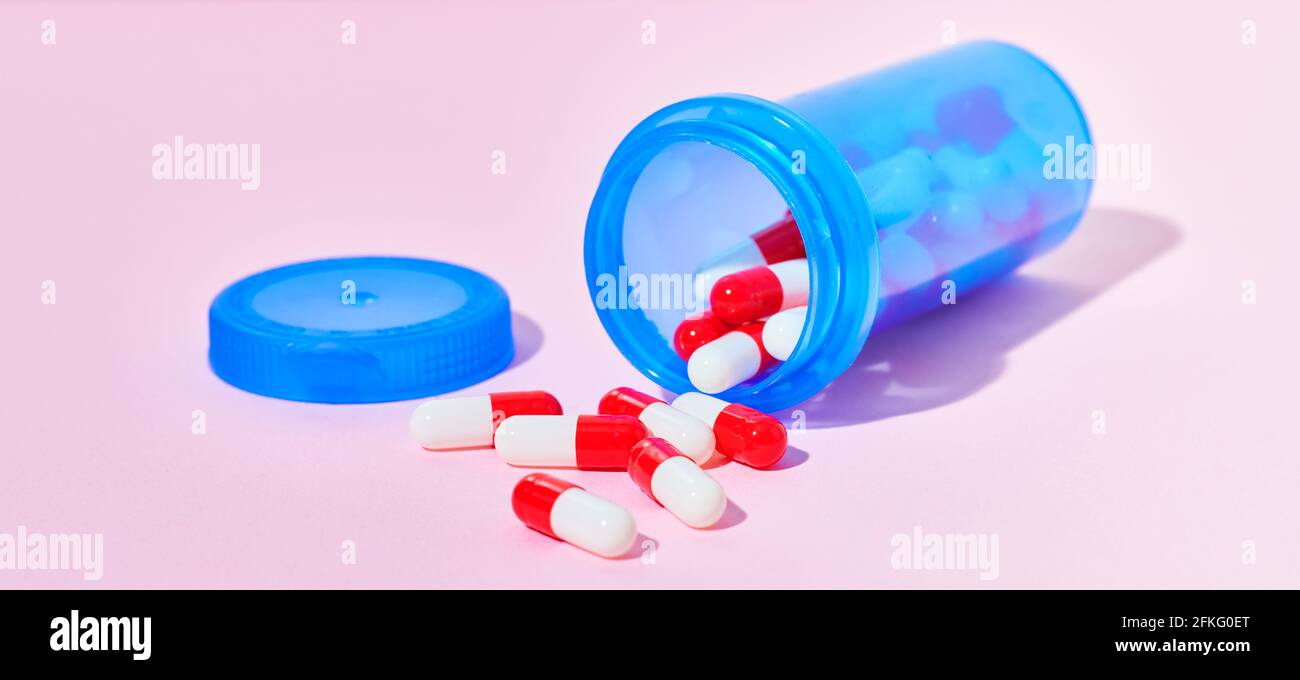 Bottle of medicine capsules on pink background Stock Photo