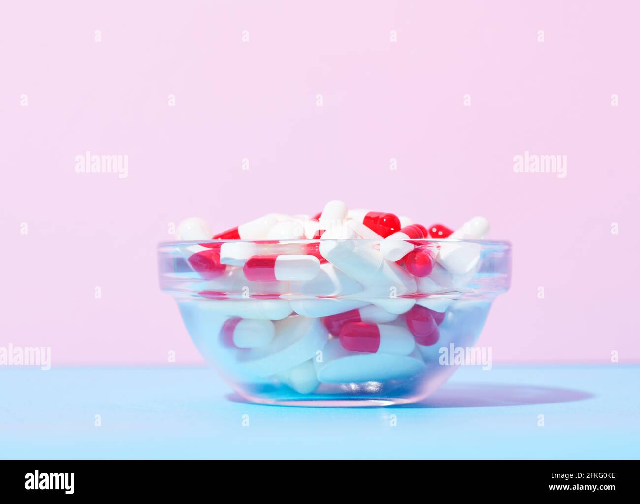 Red and white capsules and white pills in bowl Stock Photo