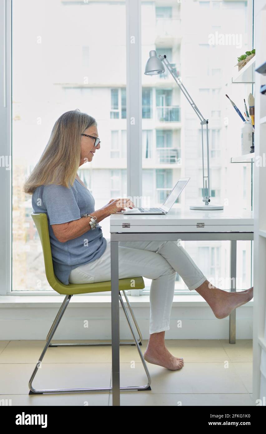 Attractive senior woman working on computer at desk Stock Photo