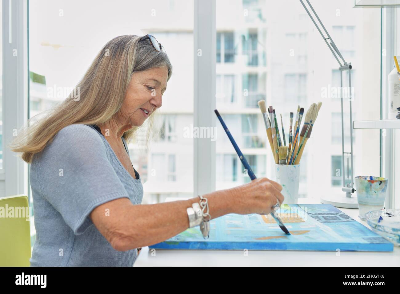 Attractive senior woman painting at desk Stock Photo