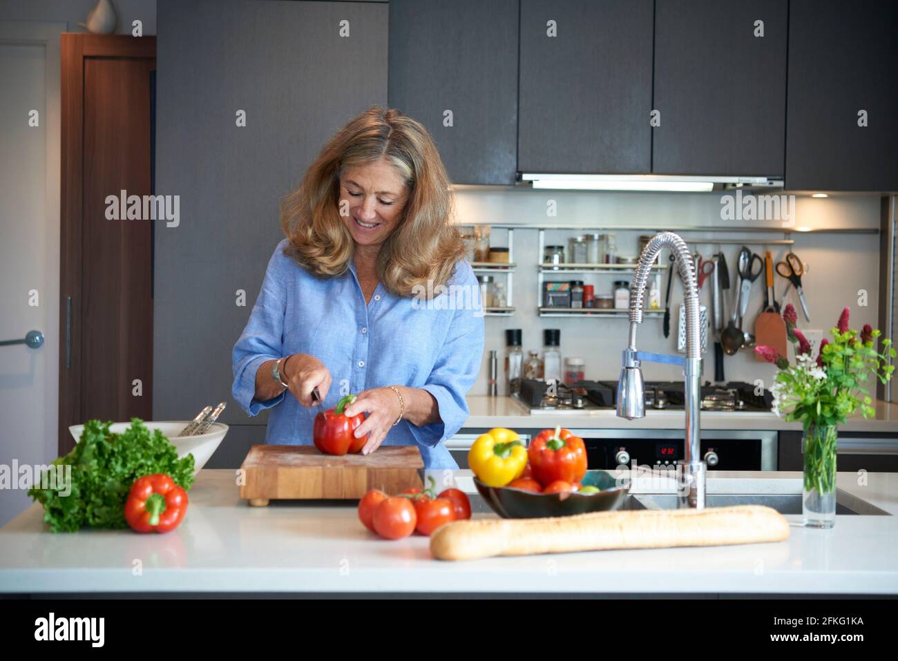 Senior older woman chopping vegetables in modern kitchen Stock Photo