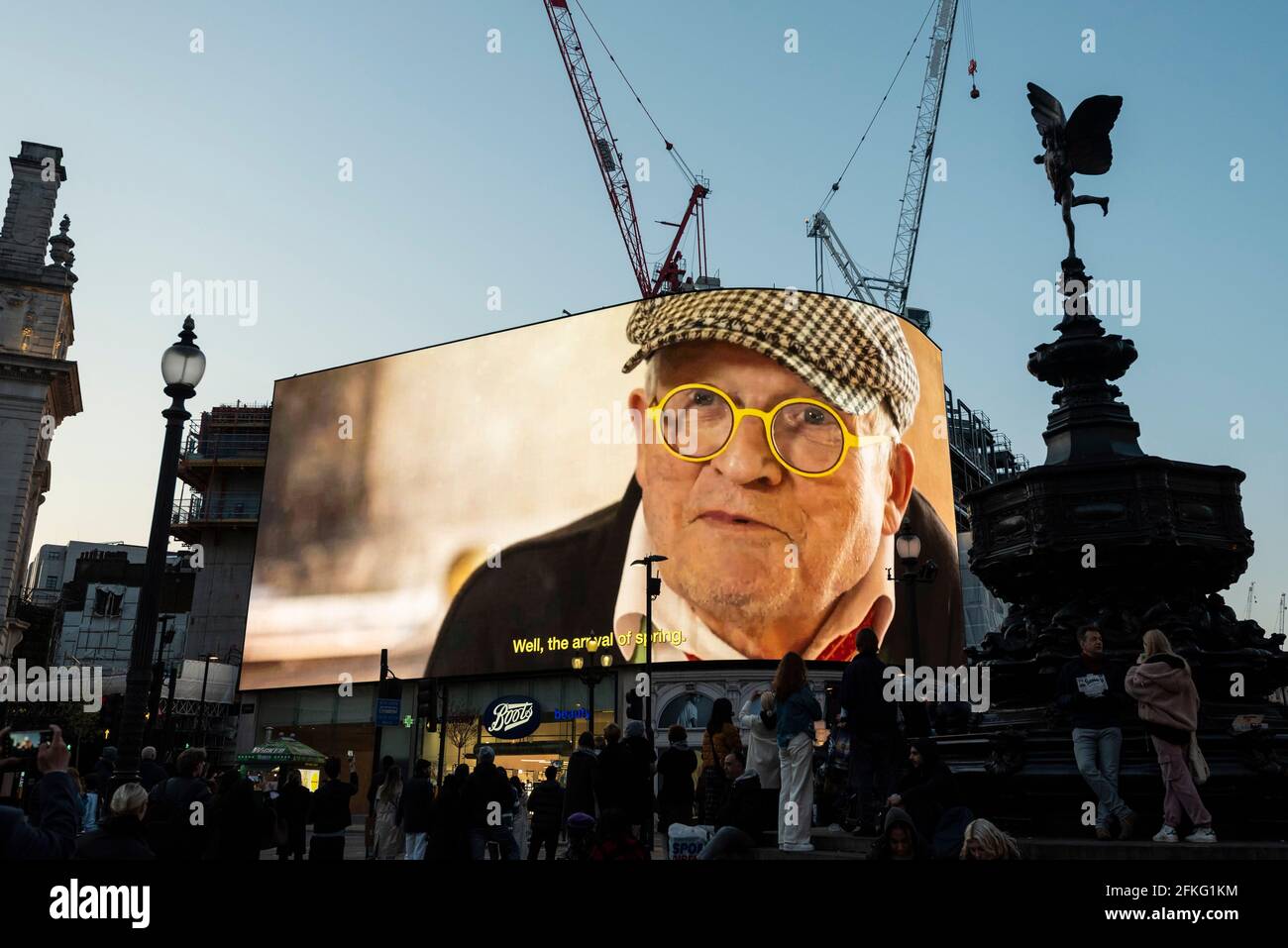 London, UK.  1 May 2021. An image of the artist ahead of David Hockney’s “Remember You Cannot Look At The Sun Or Death For Very Long” artwork, showing an animated sunrise, displayed on the giant screens at Piccadilly Circus.  It will also be displayed on screens in other cities worldwide. The work, created on an iPad, is supposed to offer a symbol of hope as the world awakens from its long lockdown and also coincides with his upcoming “The Arrival of Spring” exhibition at the Royal Academy.  In London, the work is on display nightly for the month of May. Credit: Stephen Chung / Alamy Live News Stock Photo