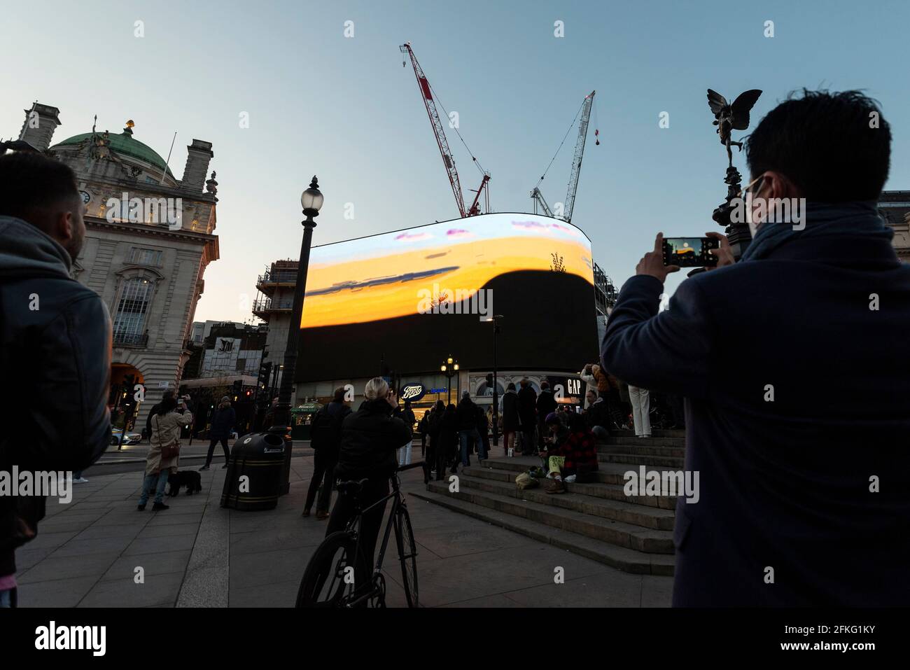London, UK.  1 May 2021.  David Hockney’s “Remember You Cannot Look At The Sun Or Death For Very Long” artwork, showing an animated sunrise, is displayed on the giant screens at Piccadilly Circus.  It will also be displayed on screens in other cities worldwide.  The work, created on an iPad, is supposed to offer a symbol of hope as the world awakens from its long lockdown and also coincides with his upcoming “The Arrival of Spring” exhibition at the Royal Academy.  In London, the work is on display nightly for the month of May.  Credit: Stephen Chung / Alamy Live News Stock Photo