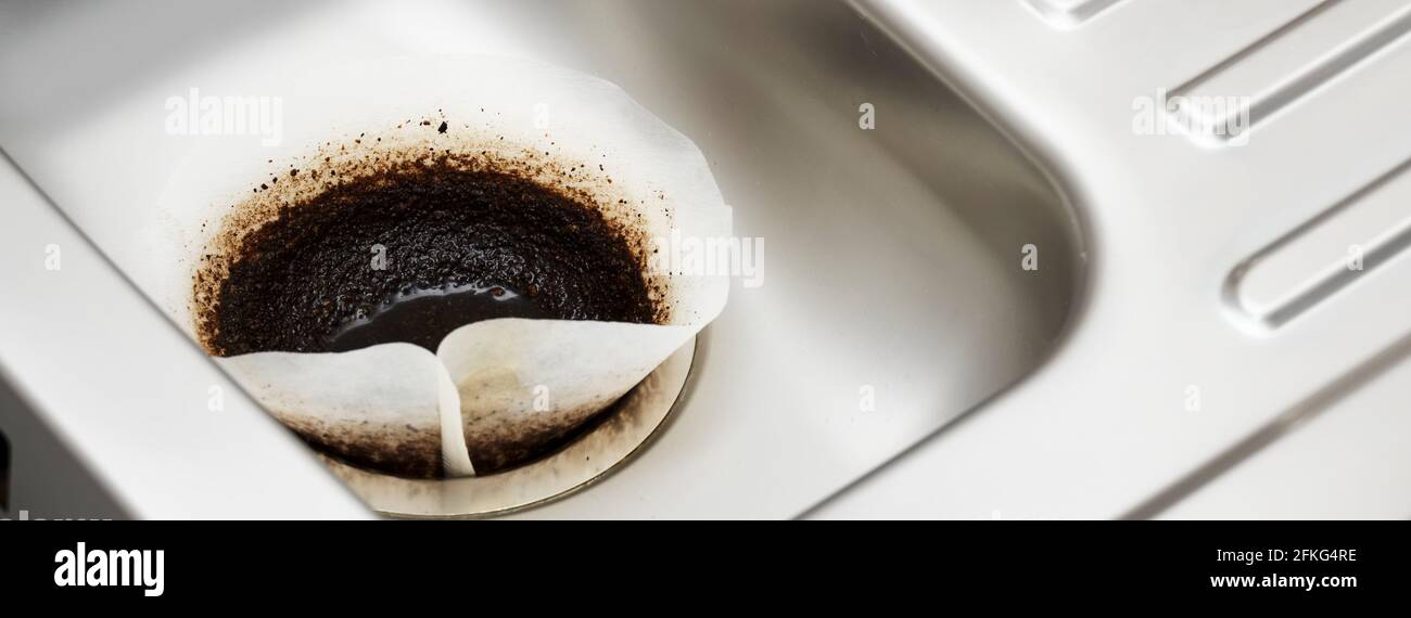 Coffee filter paper draining in kitchen sink plughole Stock Photo