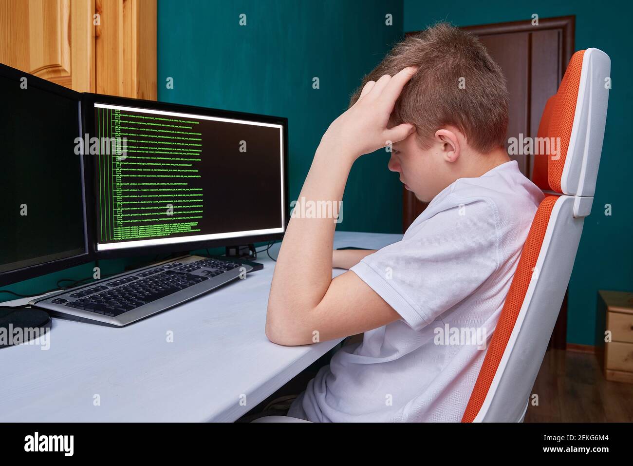 A teenage programmer thinks about the code for solving a computer problem. The programming language code on the monitor screen Stock Photo