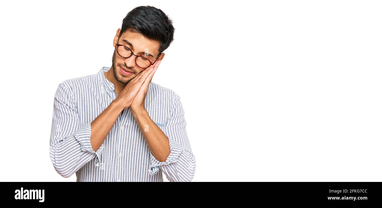 Young handsome man wearing casual clothes and glasses sleeping tired ...