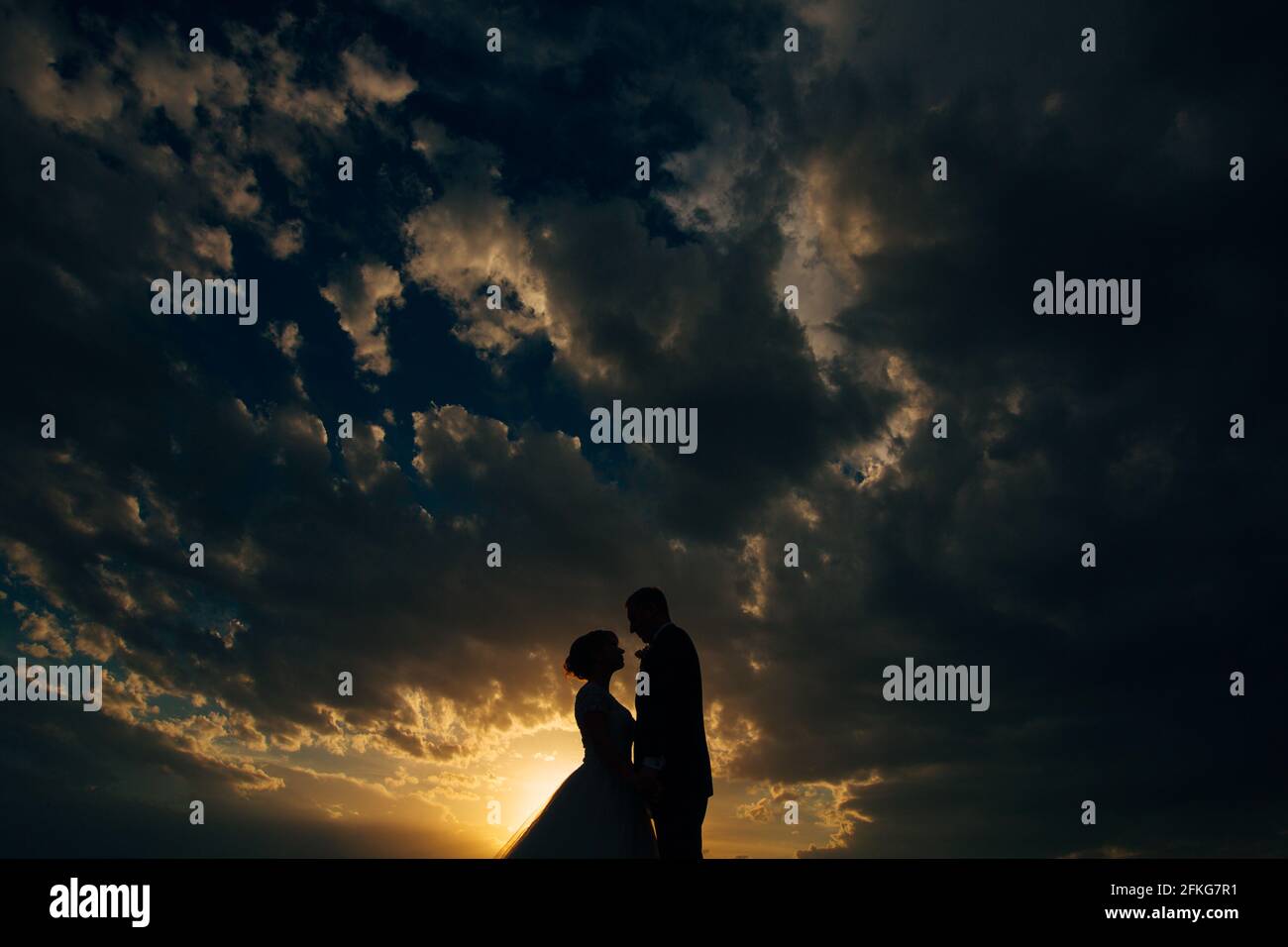 Silhouettes of the bride and groom hugging by the sunset in the evening ...