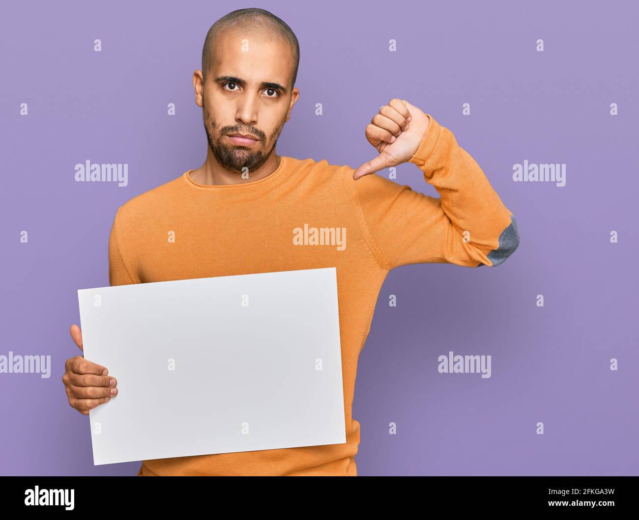 Hispanic adult man holding blank empty banner with angry face, negative ...