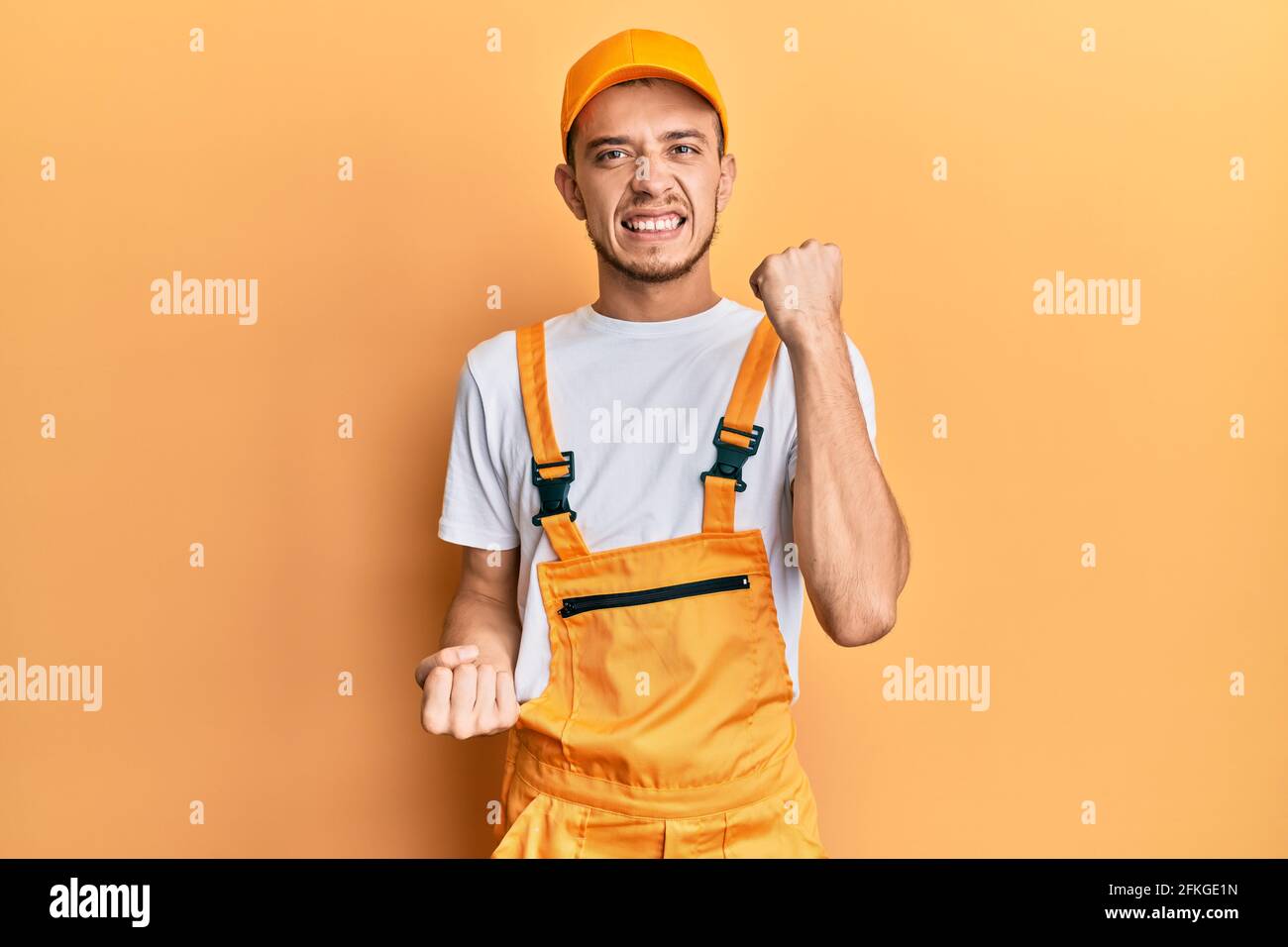 Hispanic young man wearing handyman uniform celebrating surprised and ...