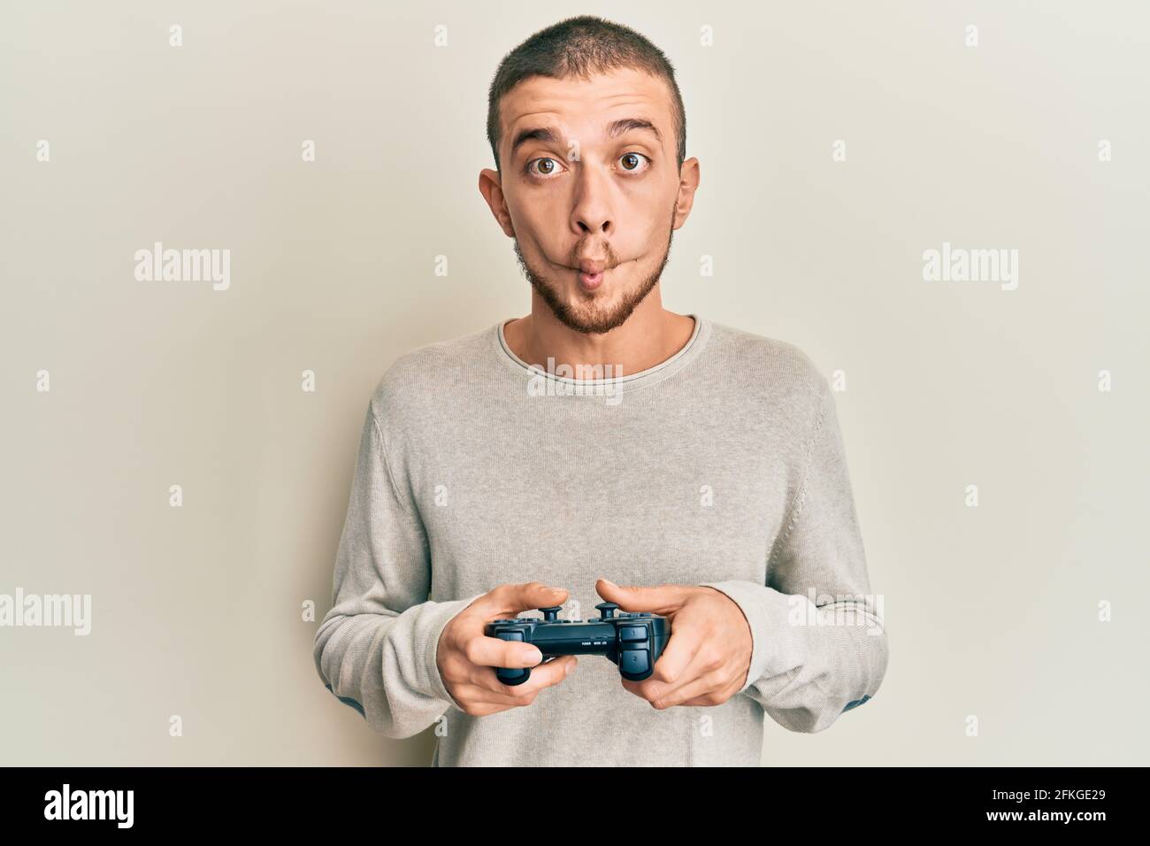 Hispanic young man playing video game holding controller making fish