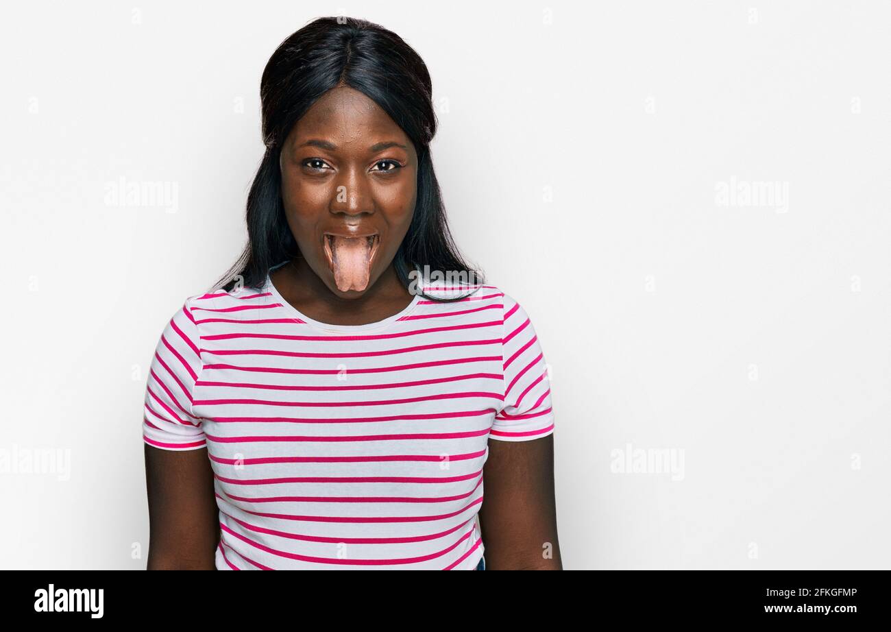 African young woman wearing casual striped t shirt sticking tongue out ...