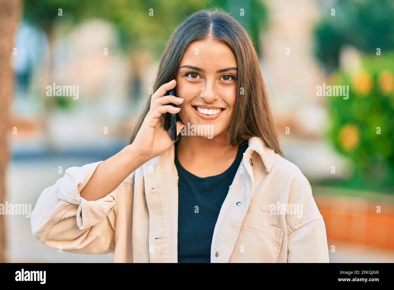 Young hispanic girl smiling happy talking on the smartphone at the park ...