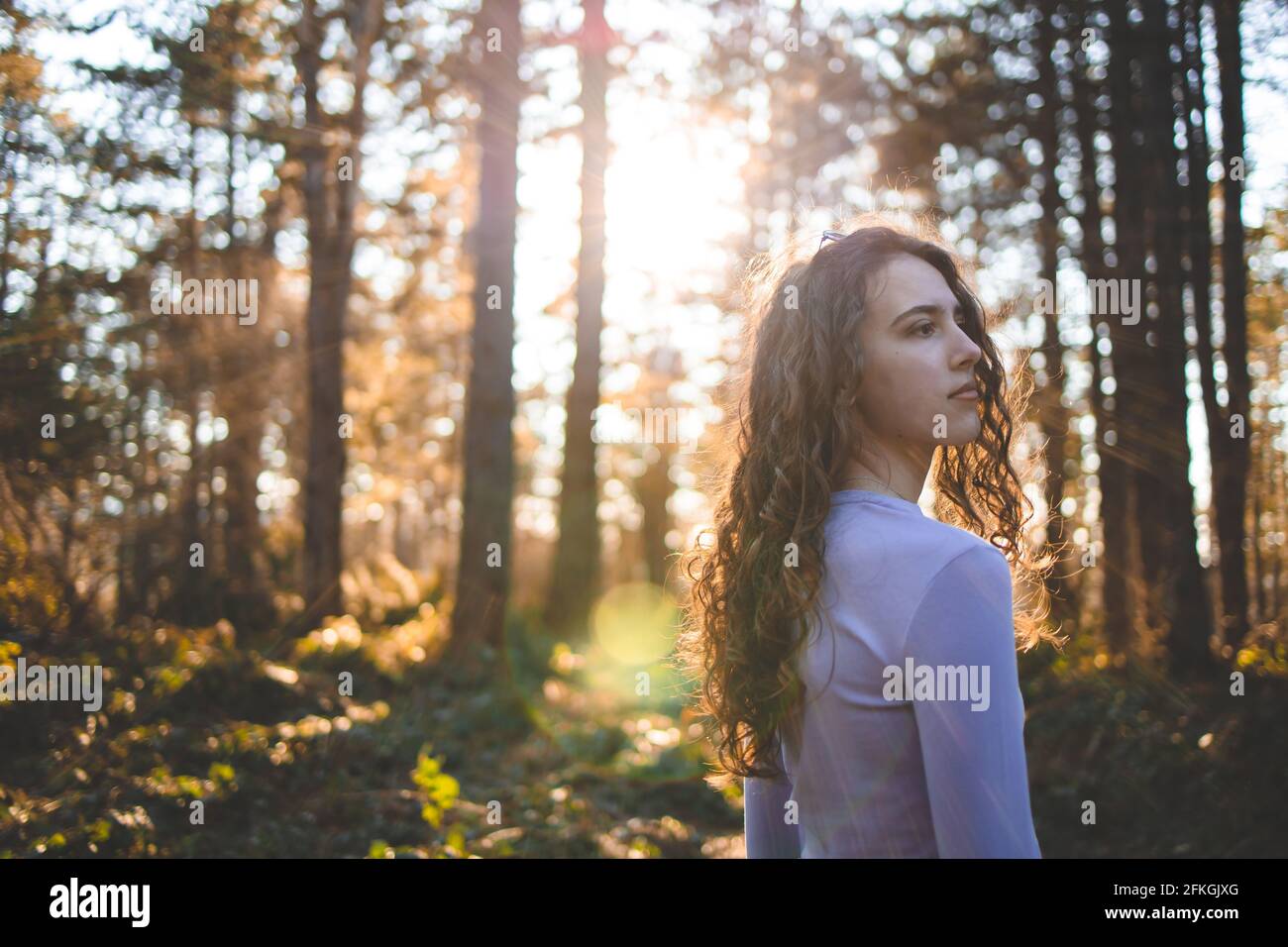 Young, brunette girl in the forest, looking at something Stock Photo