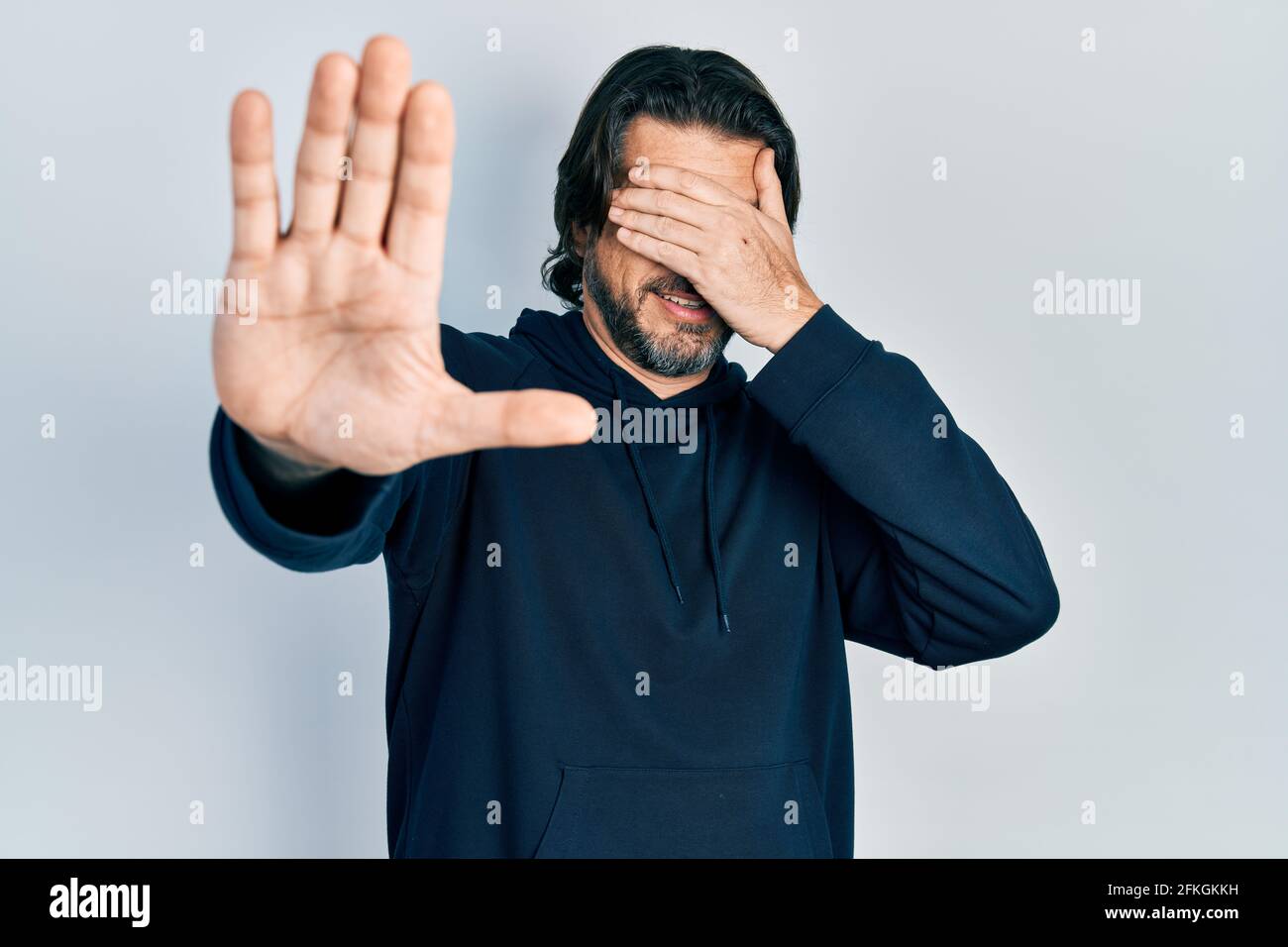 Middle age caucasian man wearing casual sweatshirt covering eyes with hands and doing stop gesture with sad and fear expression. embarrassed and negat Stock Photo