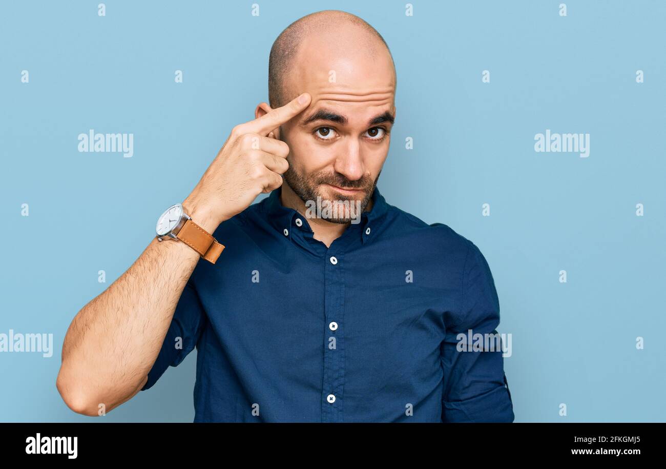 Young hispanic man wearing casual clothes pointing unhappy to pimple on forehead, ugly infection of blackhead. acne and skin problem Stock Photo