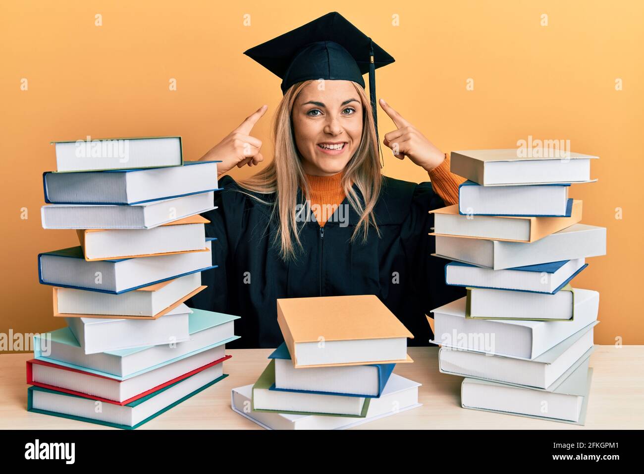 Young caucasian woman wearing graduation ceremony robe sitting on the ...