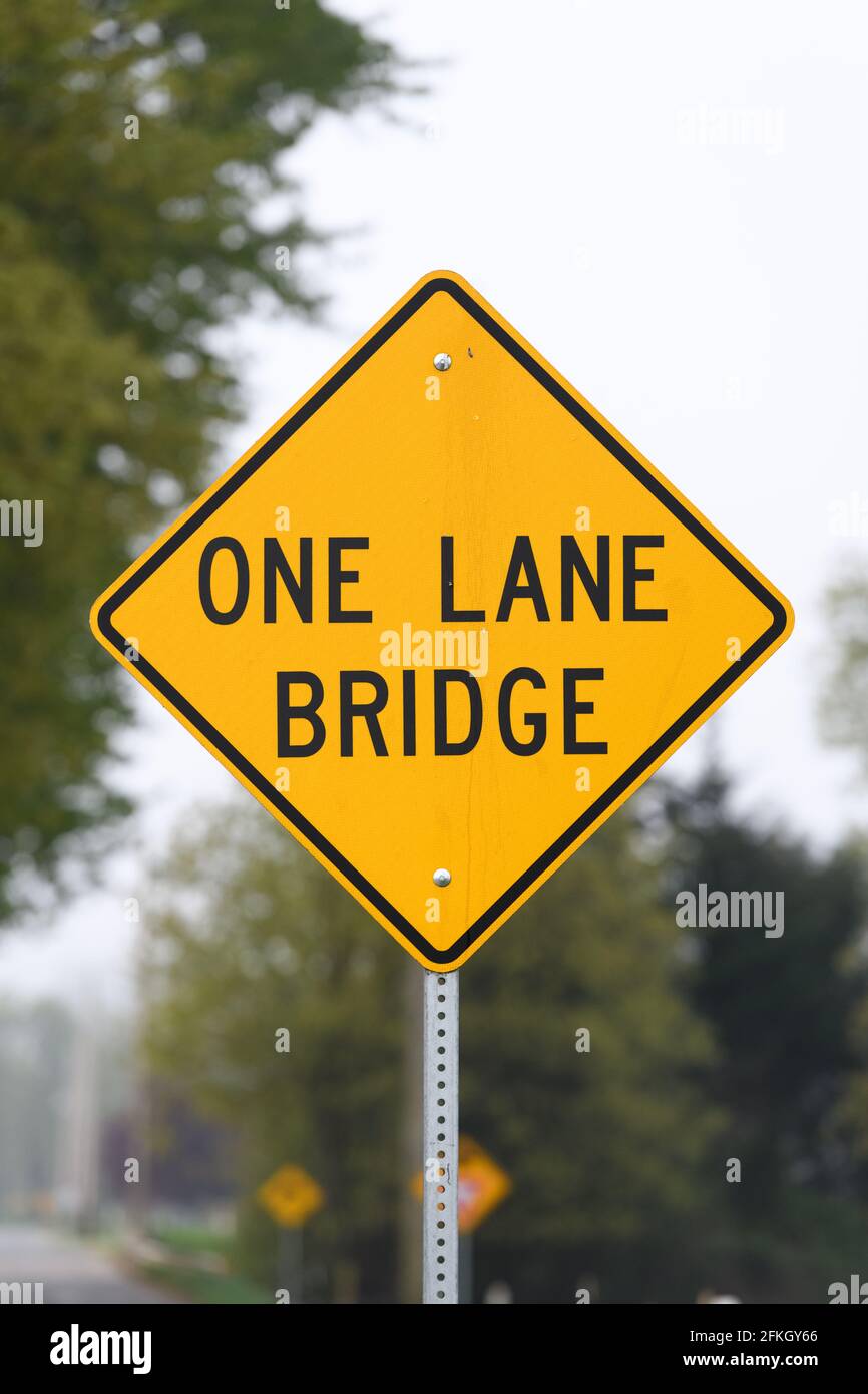 Monroe, WA, USA - April 29, 2021; A yellow and black diamond American road traffic sign with information of a one land bridge ahead Stock Photo