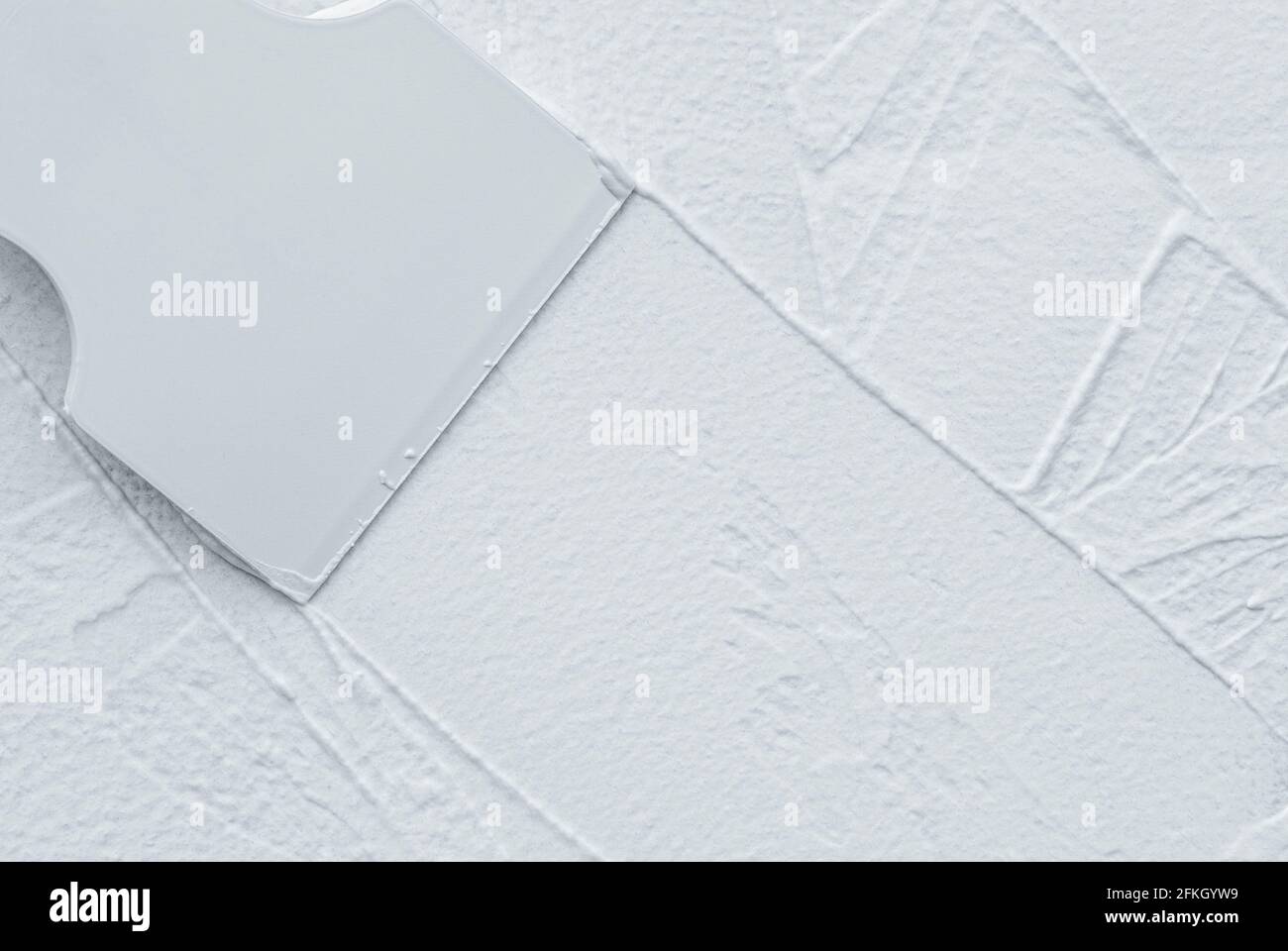 Interior finishing works, spatula applying white putty on the wall, copy space Stock Photo