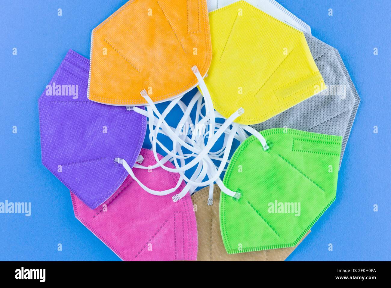 Heap of  different colors FFP2 or N95 face masks respirators without exhalation valve on blue background. Top view flat layer. Protection from covid v Stock Photo