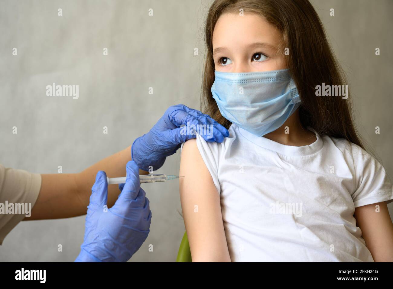 Vaccination of kid from COVID-19 or flu, cute little girl in mask during coronavirus vaccine injection. Doctor vaccinates adorable child. Concept of i Stock Photo