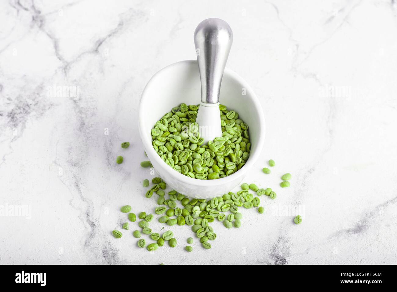 Mortar and pestle with green coffee beans on light background Stock