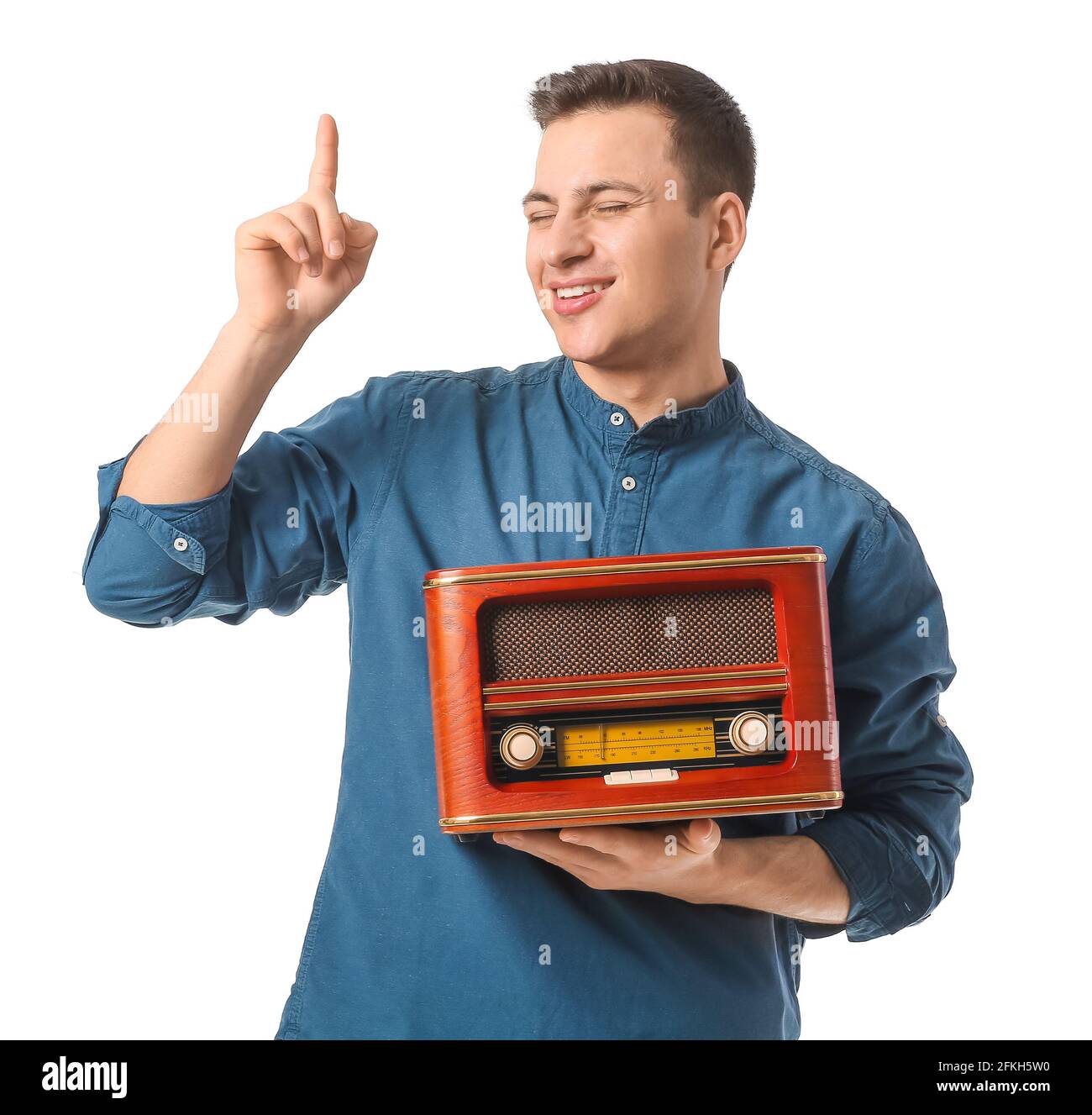 Young man listening to retro radio receiver on white background Stock