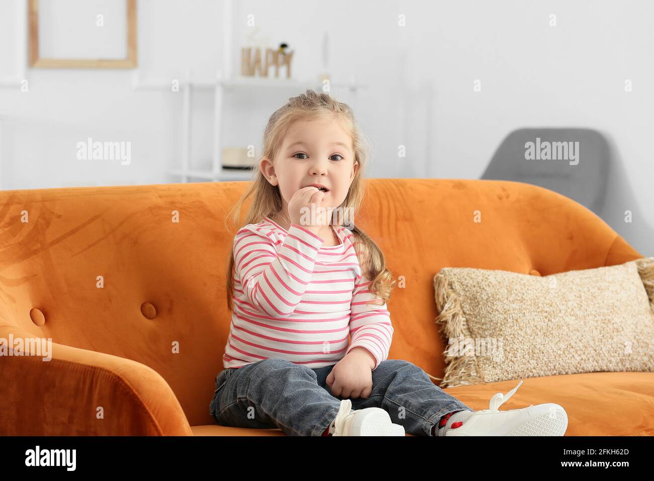 Cute little girl sitting on sofa at home Stock Photo - Alamy