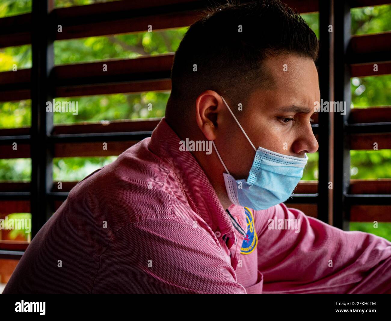 Medellin, Colombia - March 28 2021: Young Latin Man Wearing a Blue Mask Under his Nose to Prevent Covid-19 Stock Photo
