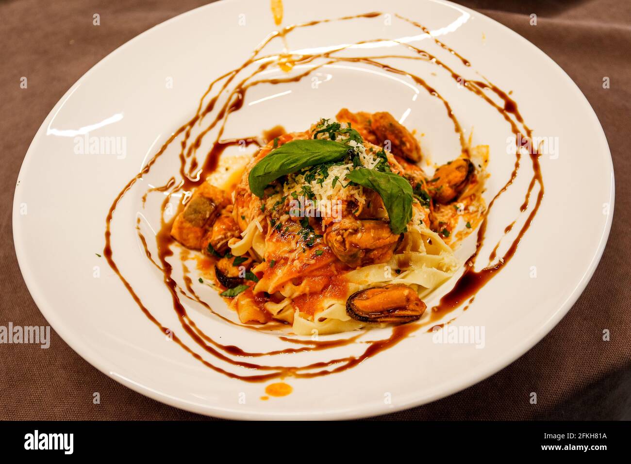 Pasta with mussels, sauce-poured serving on the white plate.  Stock Photo