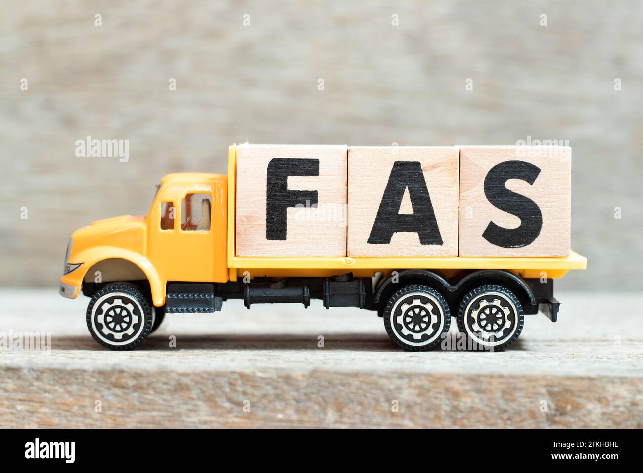 Toy truck hold alphabet letter block in word FAS (Abbreviation of Fetal alcohol syndrome, Free alongside or Financial accounting standards) on wood ba Stock Photo