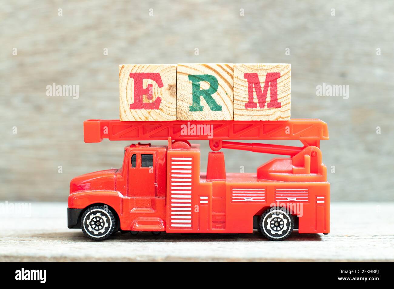 Fire ladder truck hold letter block in word ERM (Abbreviation of Enterprise risk management) on wood background Stock Photo