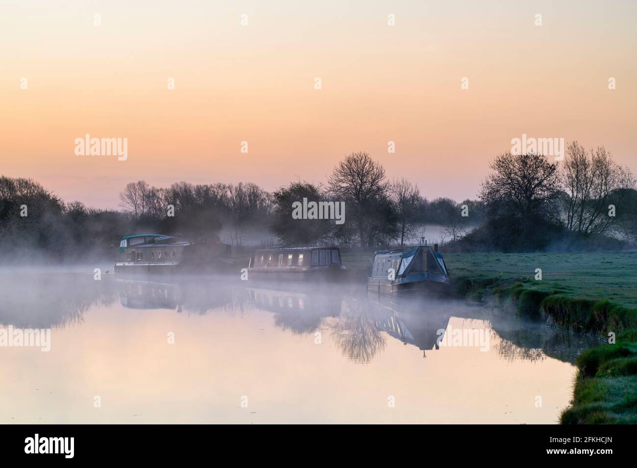 Narrowboats on the river thames at dawn in the spring mist. Lechlade on Thames, Cotswolds, Gloucestershire, England Stock Photo