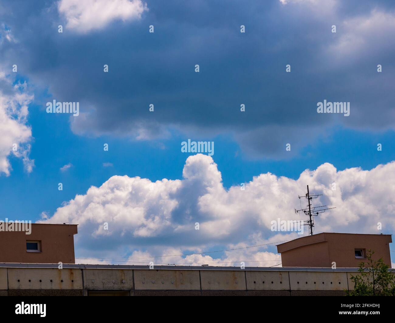 Cloud - towering cumulus - forming in the distance above the roof of the house Stock Photo