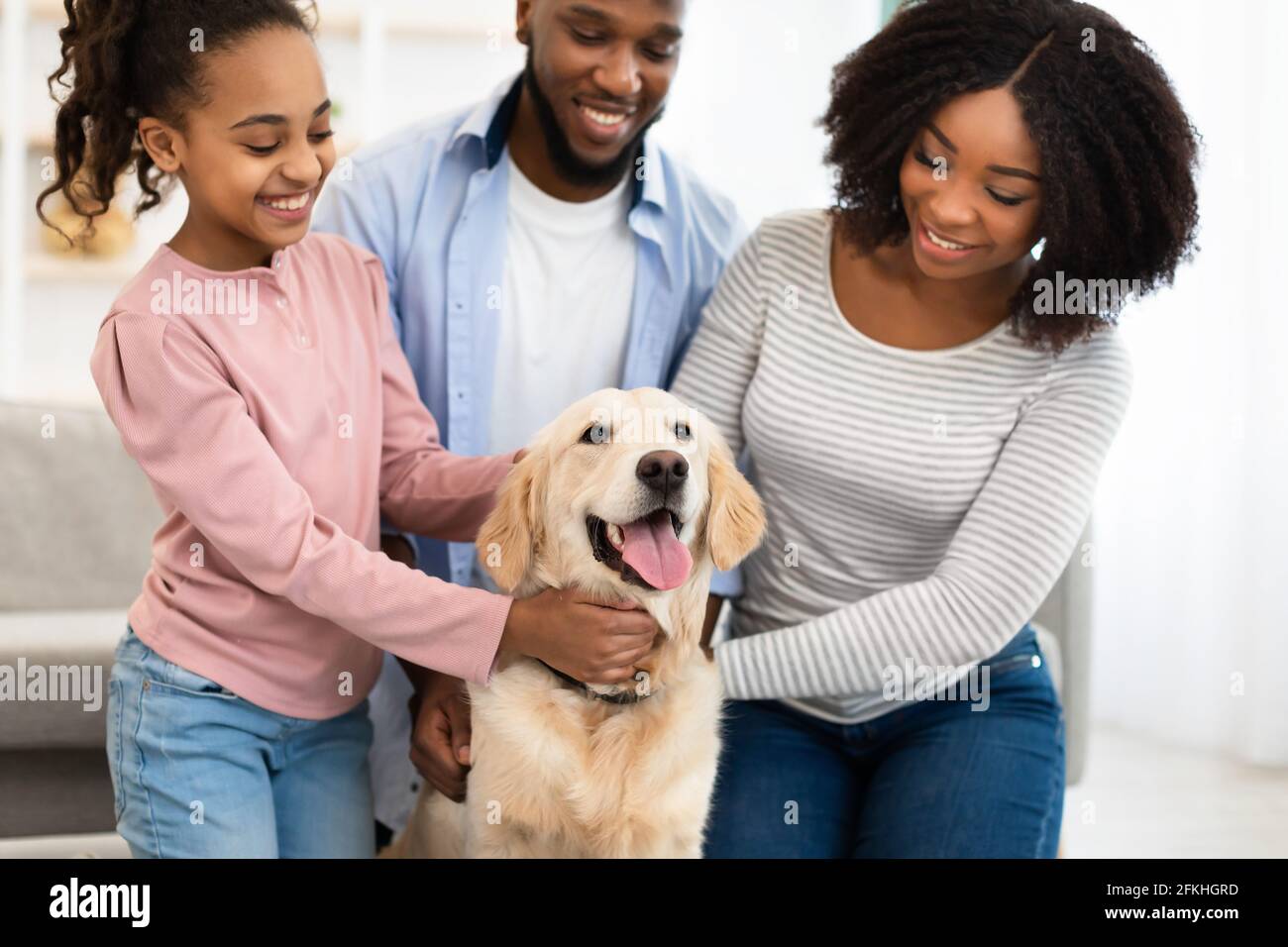 Young black family hugging dog posing at home Stock Photo