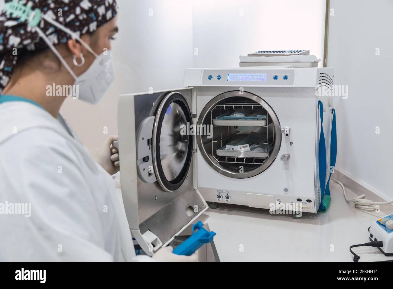 The dentist's assistant insert the packaged dental instrument to the autoclave to sterilise. Modern dental equipments. Stock Photo