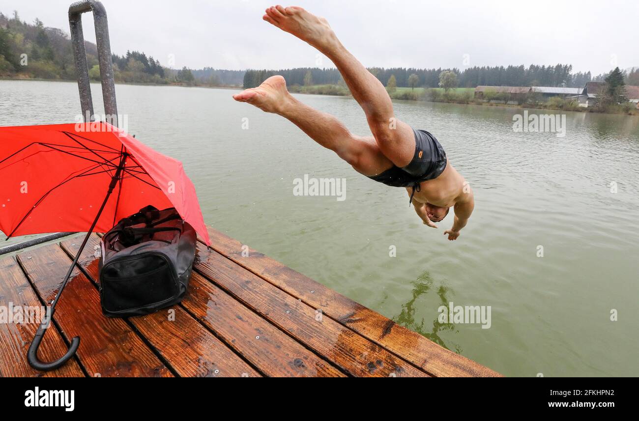 Bad Saulgau, Germany. 02nd May, 2021. A man jumps head first into a lake from a jetty in the morning when the outside temperature is 4 degrees Celsius and it is raining. Credit: Thomas Warnack/dpa/Alamy Live News Stock Photo