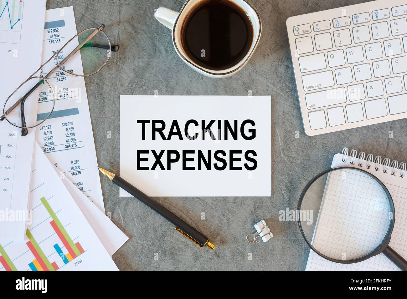 Tracking Expenses is written in a document on the office desk with