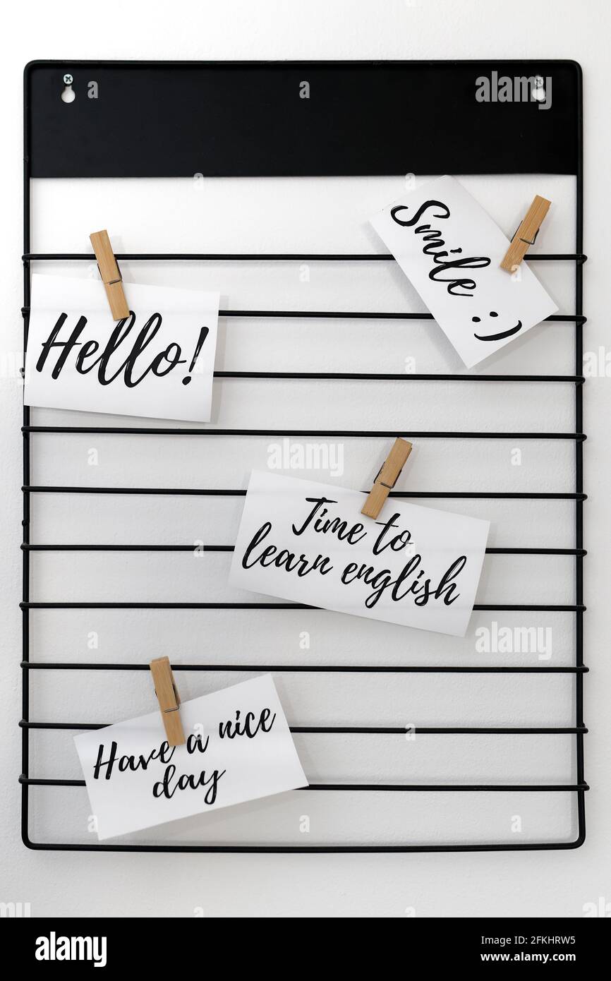 Words of the English language written on sheets of paper attached to a metal hanger with clips Stock Photo