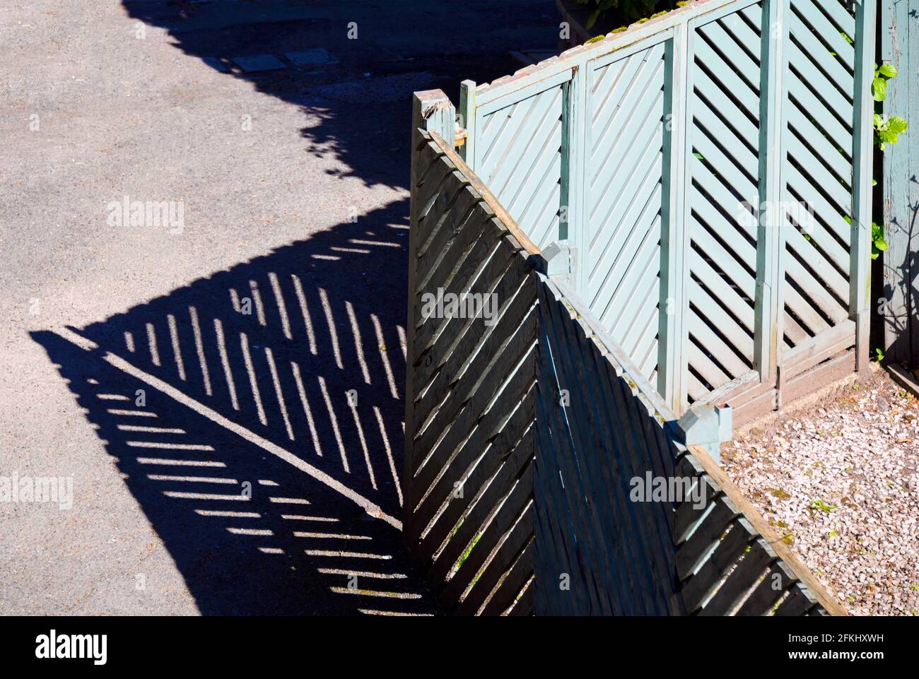 Green painted wooden garden gate and fence with shadows. Stock Photo