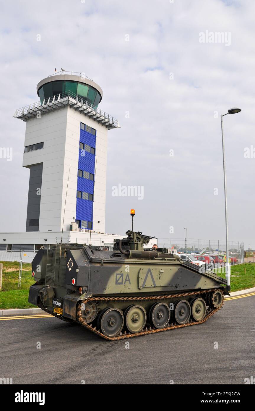 Armoured Personnel Carrier, APC tank driving past air traffic control tower at London Southend Airport, UK. Privately owned for show. Security concept Stock Photo
