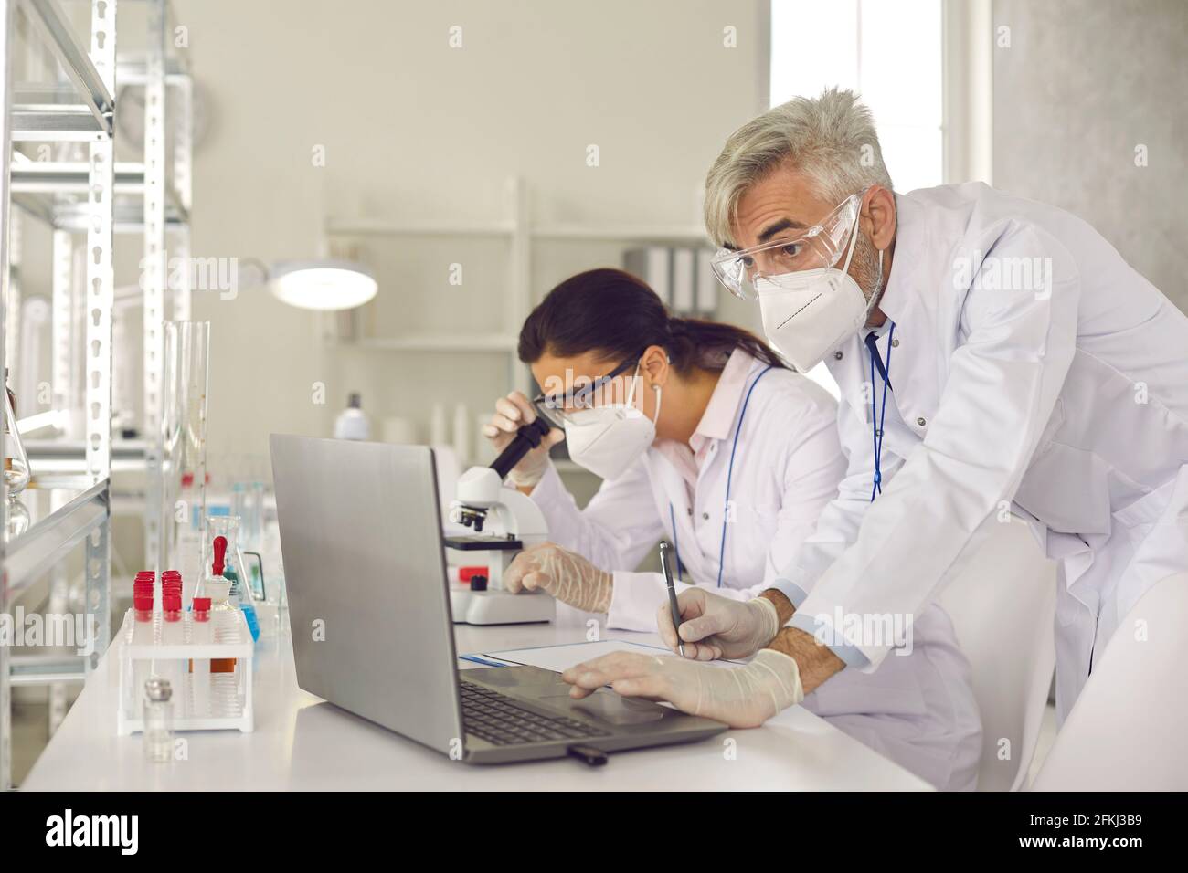 Microbiologist biotechnology researcher in facial mask conducting experiment Stock Photo