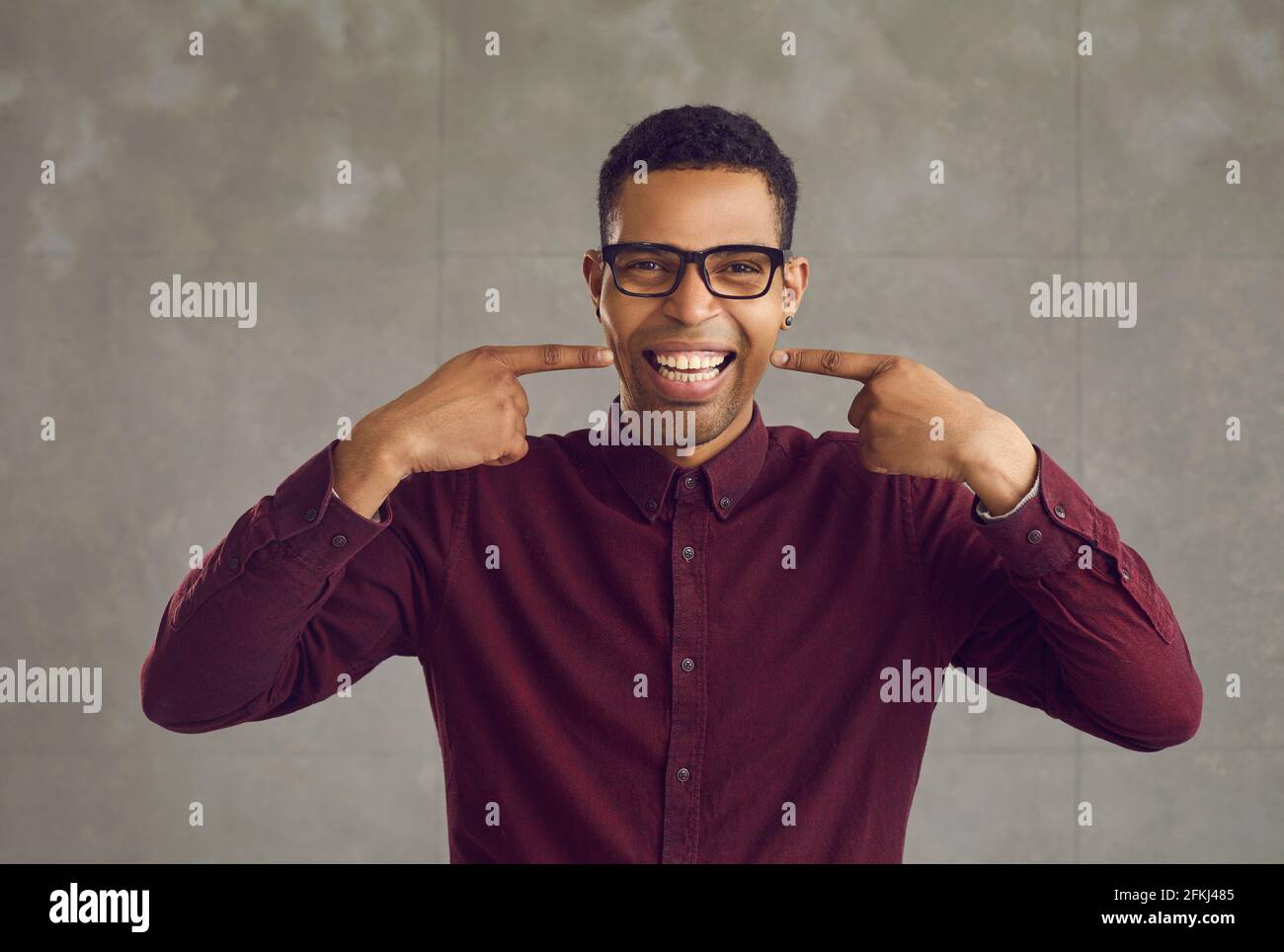 Young african american man pointing showing white teeth smile studio shot Stock Photo