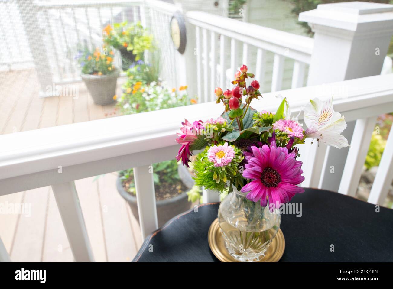 USA  a vase with fresh flowers in a screened in porch looking out to a deck with flower in the spring Stock Photo