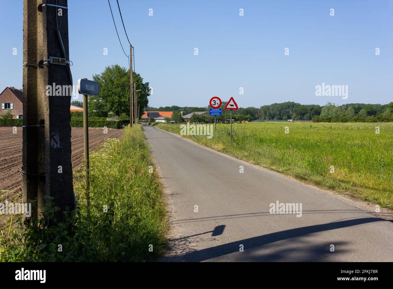 Rural street with overhead electricity cables in Grobbendonk on a sunny spring day Stock Photo