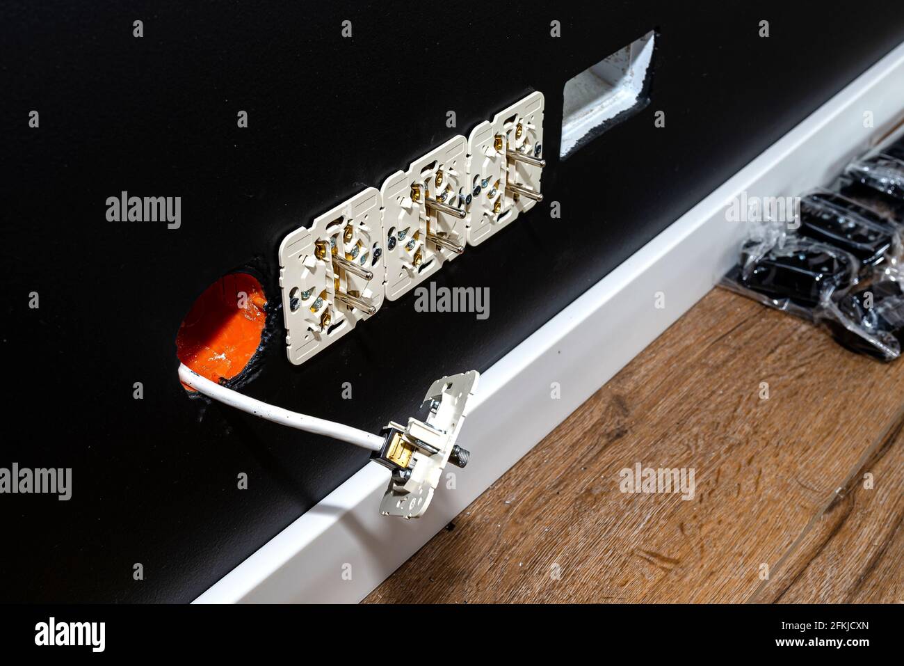 Double grounded electric sockets mounted in the black wall and a