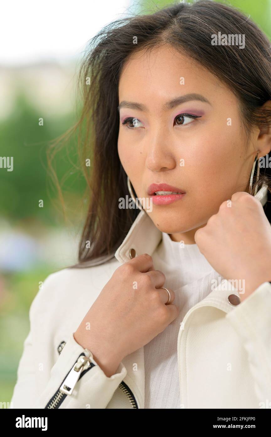 https://c8.alamy.com/comp/2FKJFP0/a-young-pretty-mongolian-woman-with-a-white-leather-jacket-in-an-urban-park-2FKJFP0.jpg